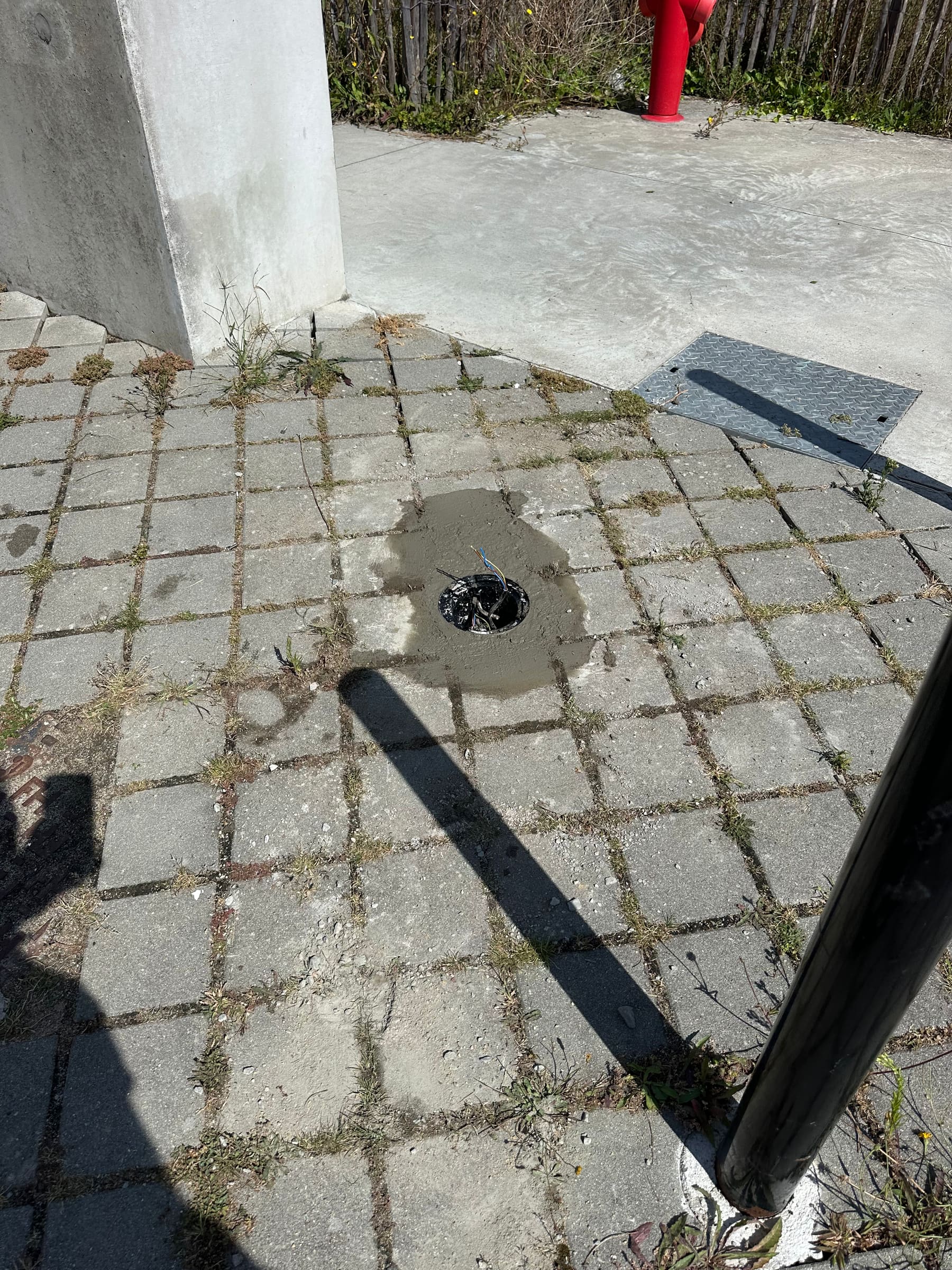 Fourreau ouvert dans une cour pavée, câbles d’alimentation à raccorder