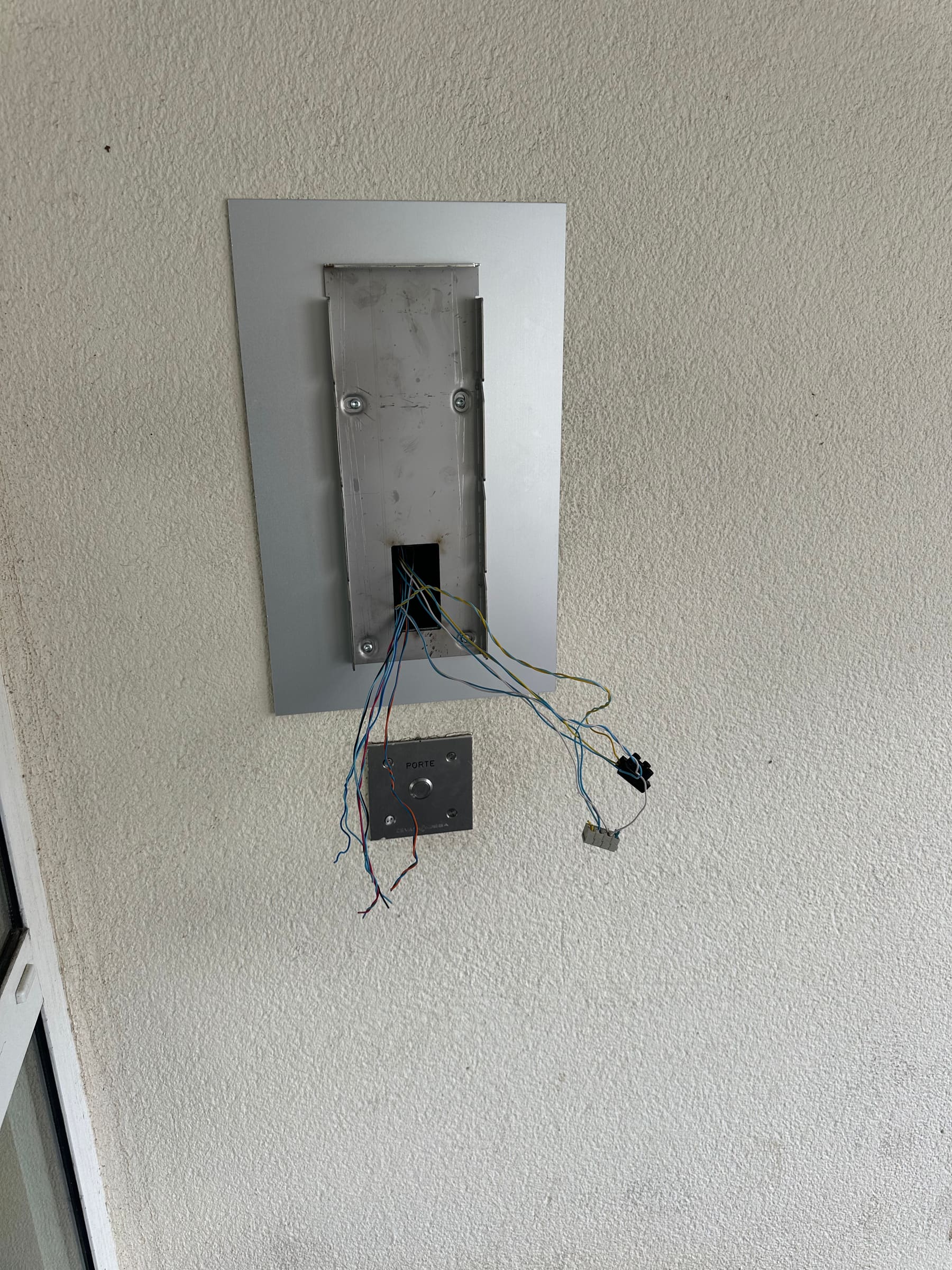 Platine d’interphone déposée pendant un dépannage, fils en attente de raccordement